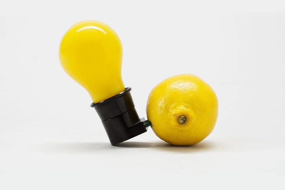 Eine gelbe Glühlampe steckt in einer Zitrone.